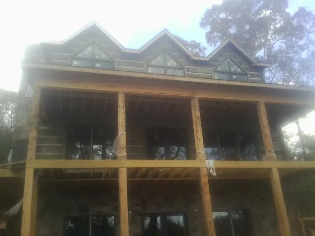Dormers and porch framing on a large log home under construction — Roof Coating work by our crew in Nelson
